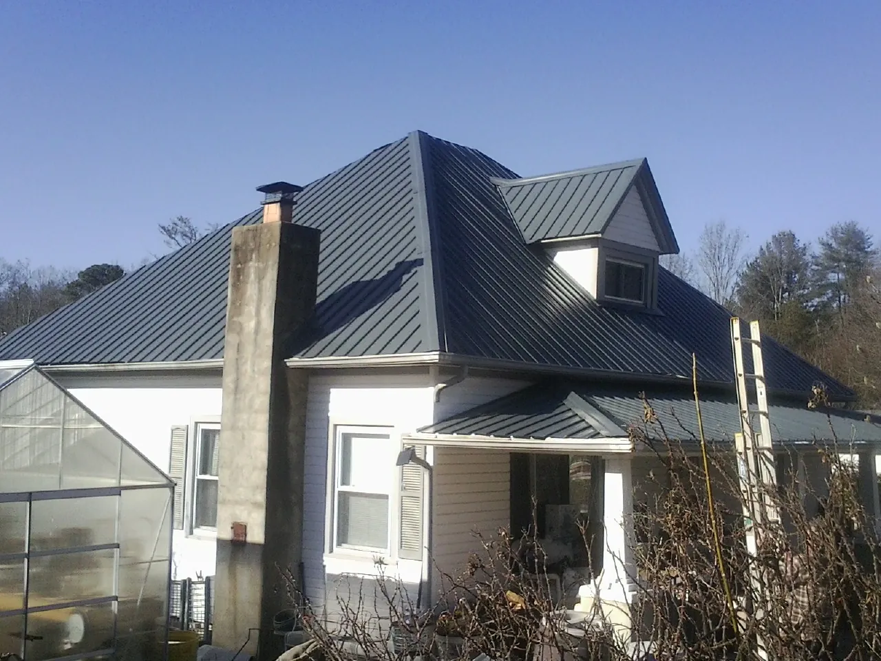 Dark blue standing seam metal roof on a white farmhouse with dormer — Slate & Tile Roof Repair by Roofing Brothers in Satsuma